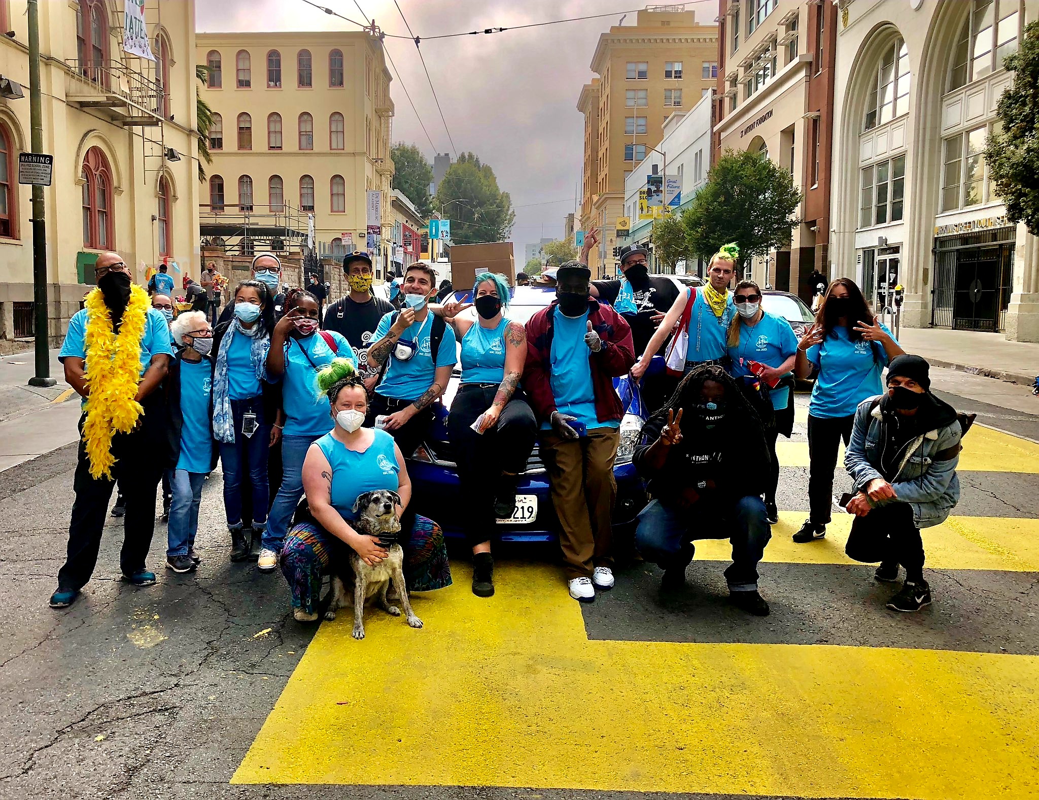 A group of people wearing blue DOPE Project shirts and face masks posing in the street during the Overdose Awareness Day event in San Francisco, 2020.